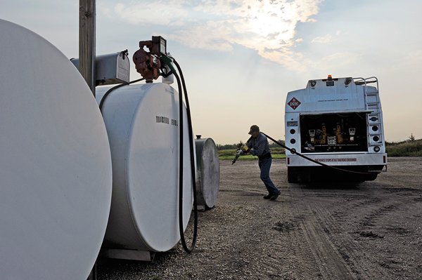 Man walking hose from a propane truck to a tank