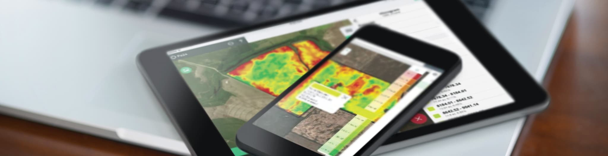 Tablet and phone on a table with precision ag software on screens