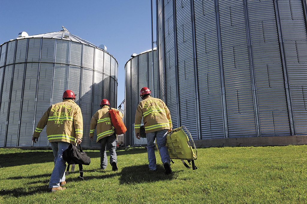 Three firefighters wearing PPE walking towards grain bins