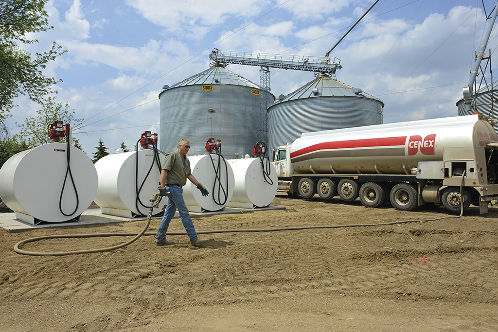 Man walking hose back from propane tanks to Cenex refueling truck