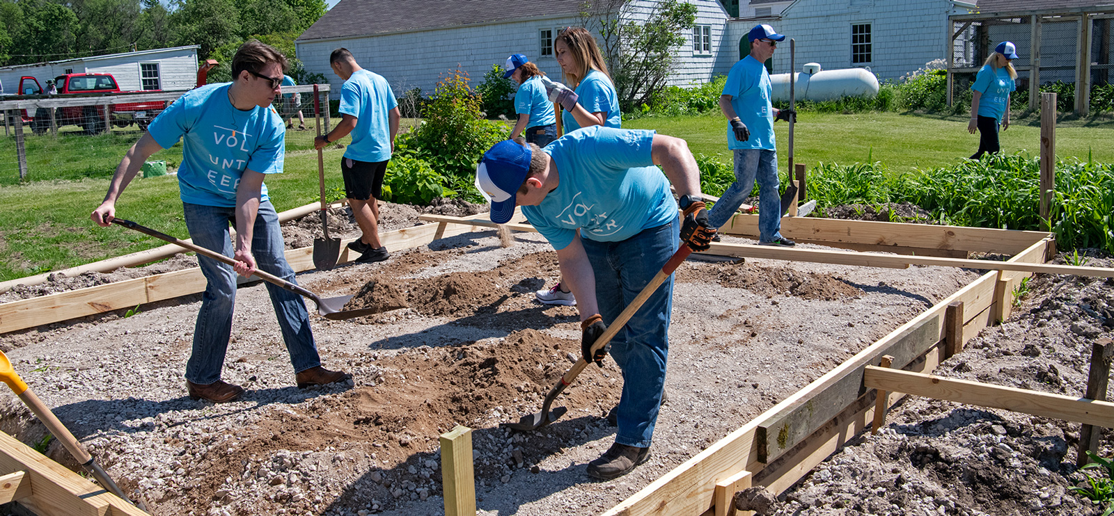 Group of people working together digging plots in a community garden